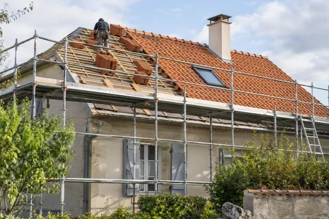 Toiture en tuiles en cours de rénovation derrière un échafaudage — illustration