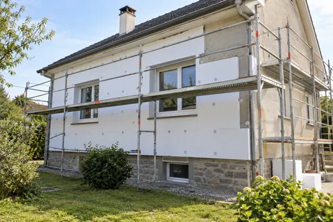 Maison avec façade partiellement isolée et échafaudage — illustration