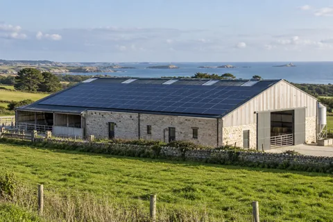 Toiture agricole équipée de panneaux photovoltaïques avec la mer au loin — illustration